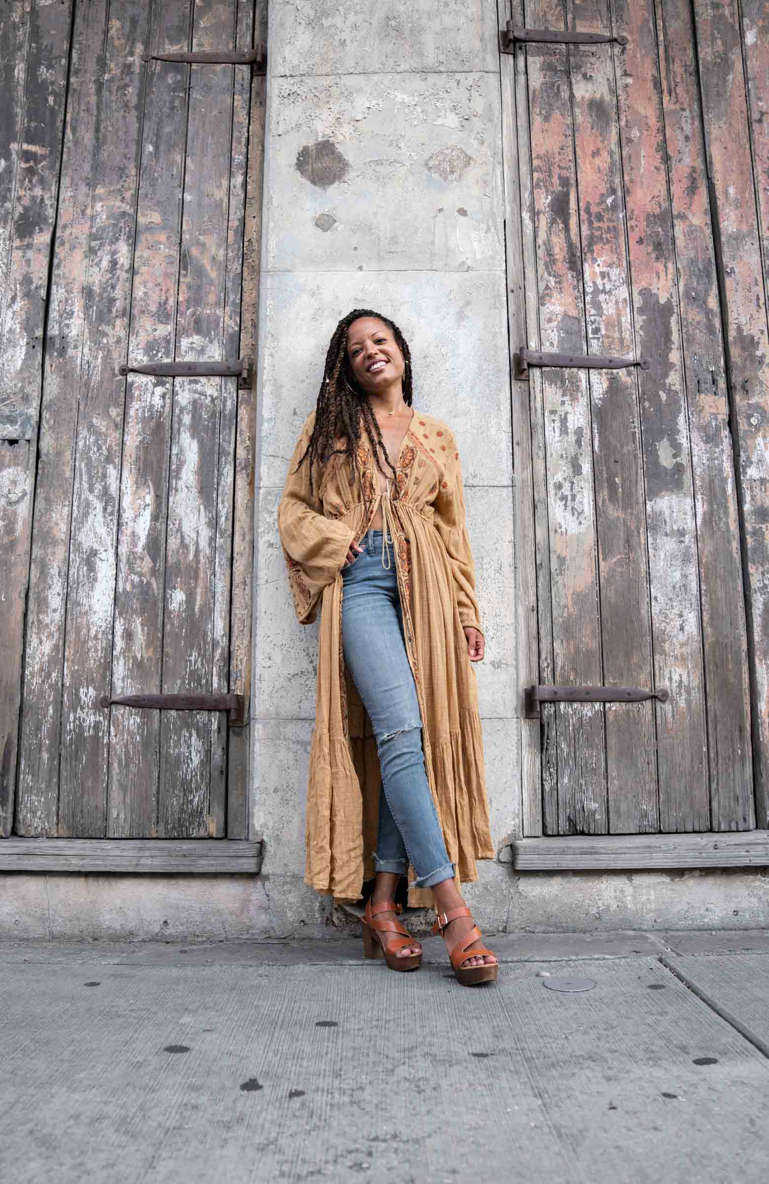 A woman modeling and smiling in a cool outfit on the sidewalk in the New Orleans French Quarter