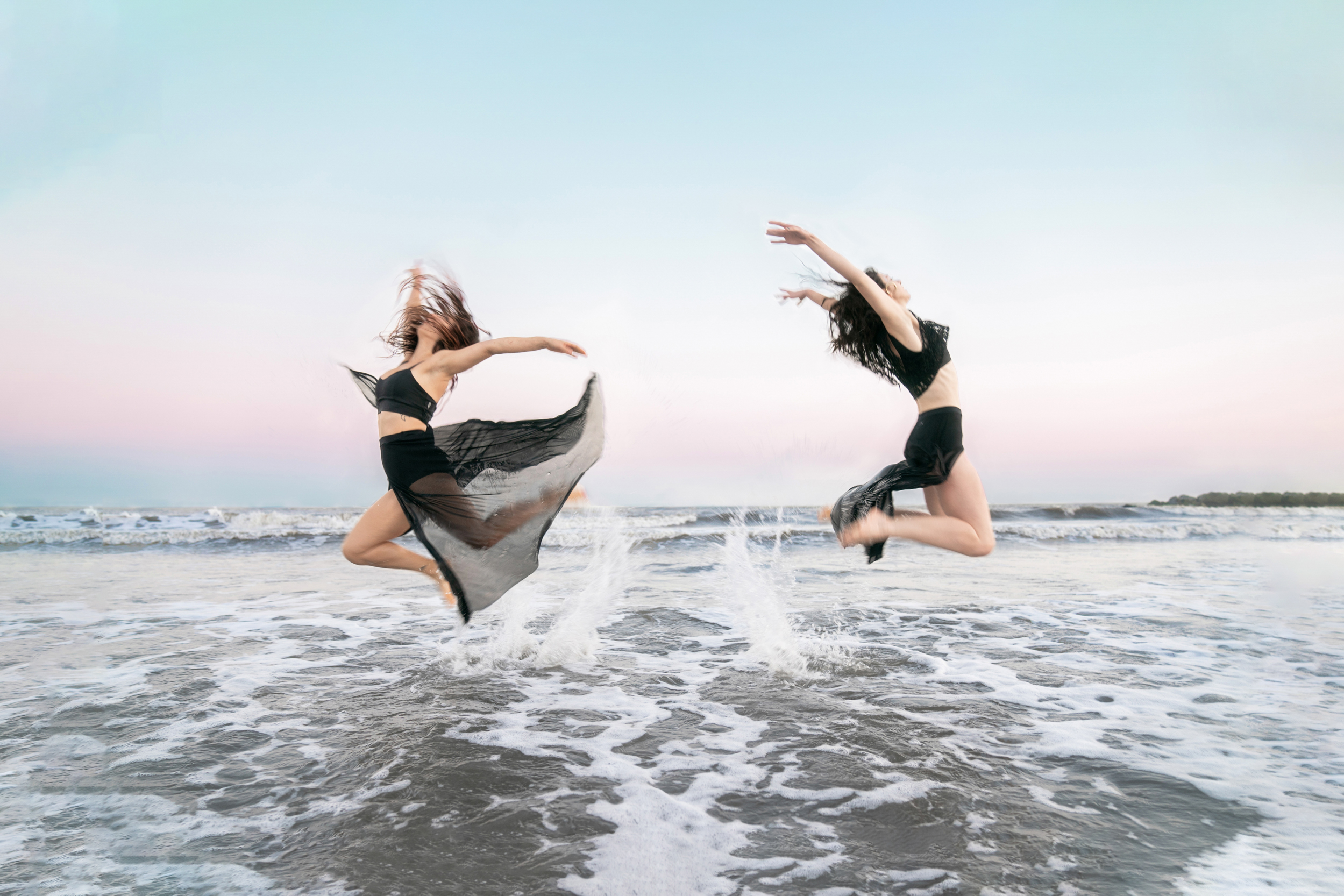 Dancers jumping and performing on the beach at sunset along Louisiana Gulf Coast