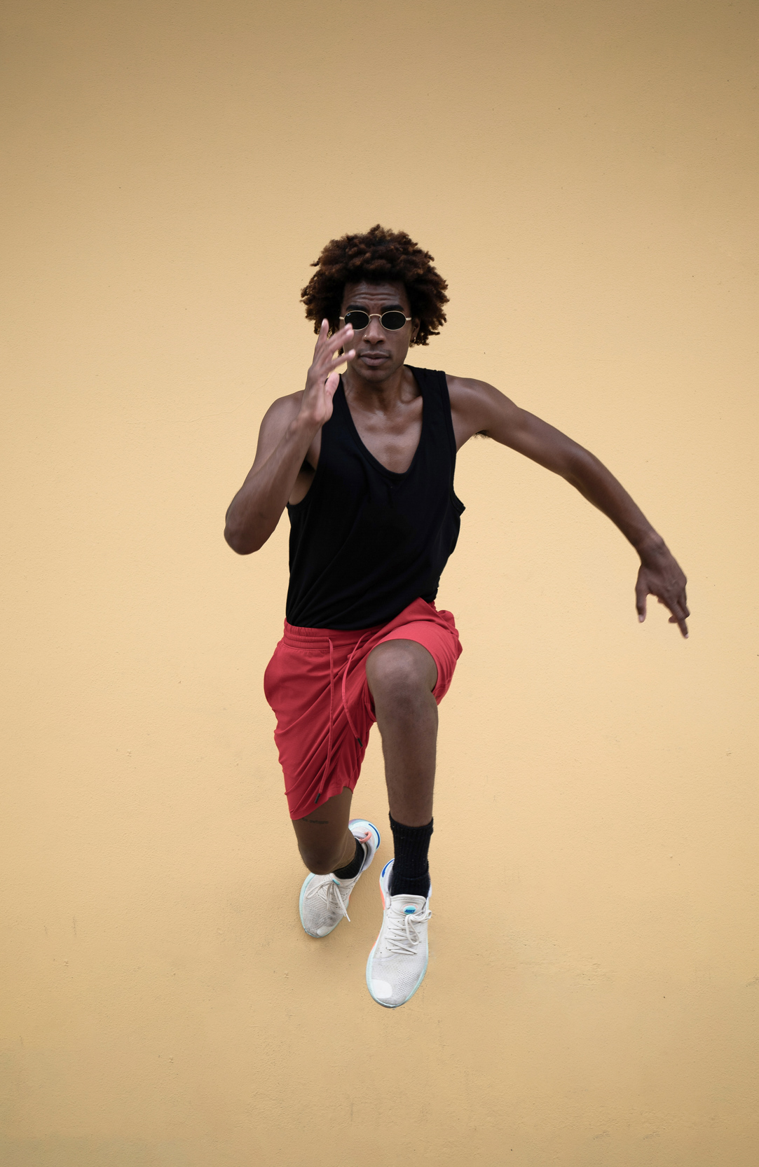 Model jumping in the air wearing fashionable outfit and glasses in New Orleans