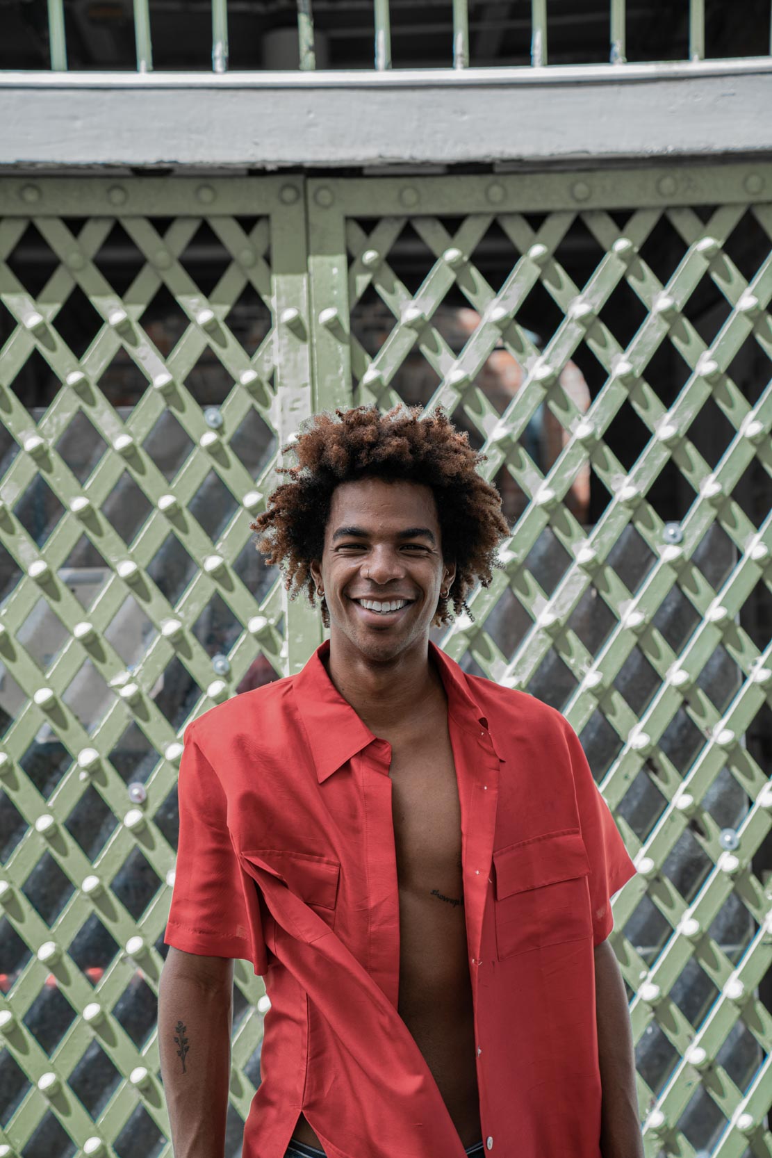 A shirtless model and dancer smiling along a green gate in the New Orleans French Quarter