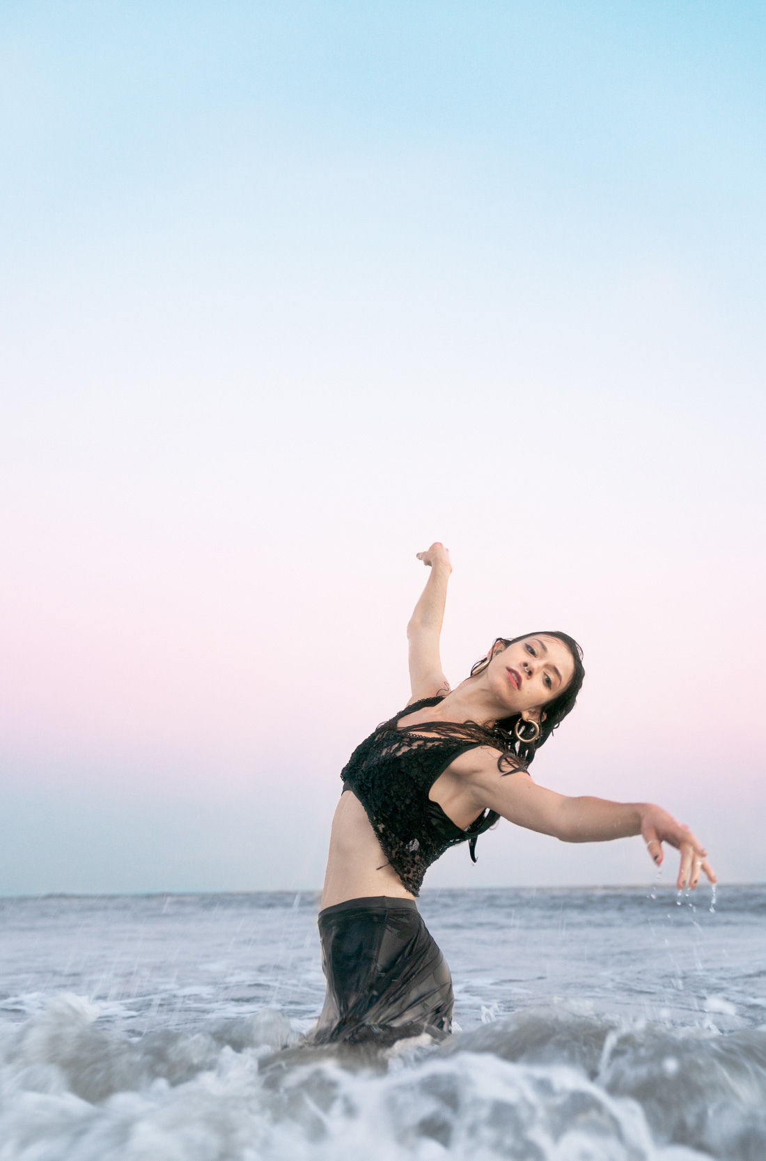 Woman dancing in the ocean at sunset along Louisiana Gulf Coast