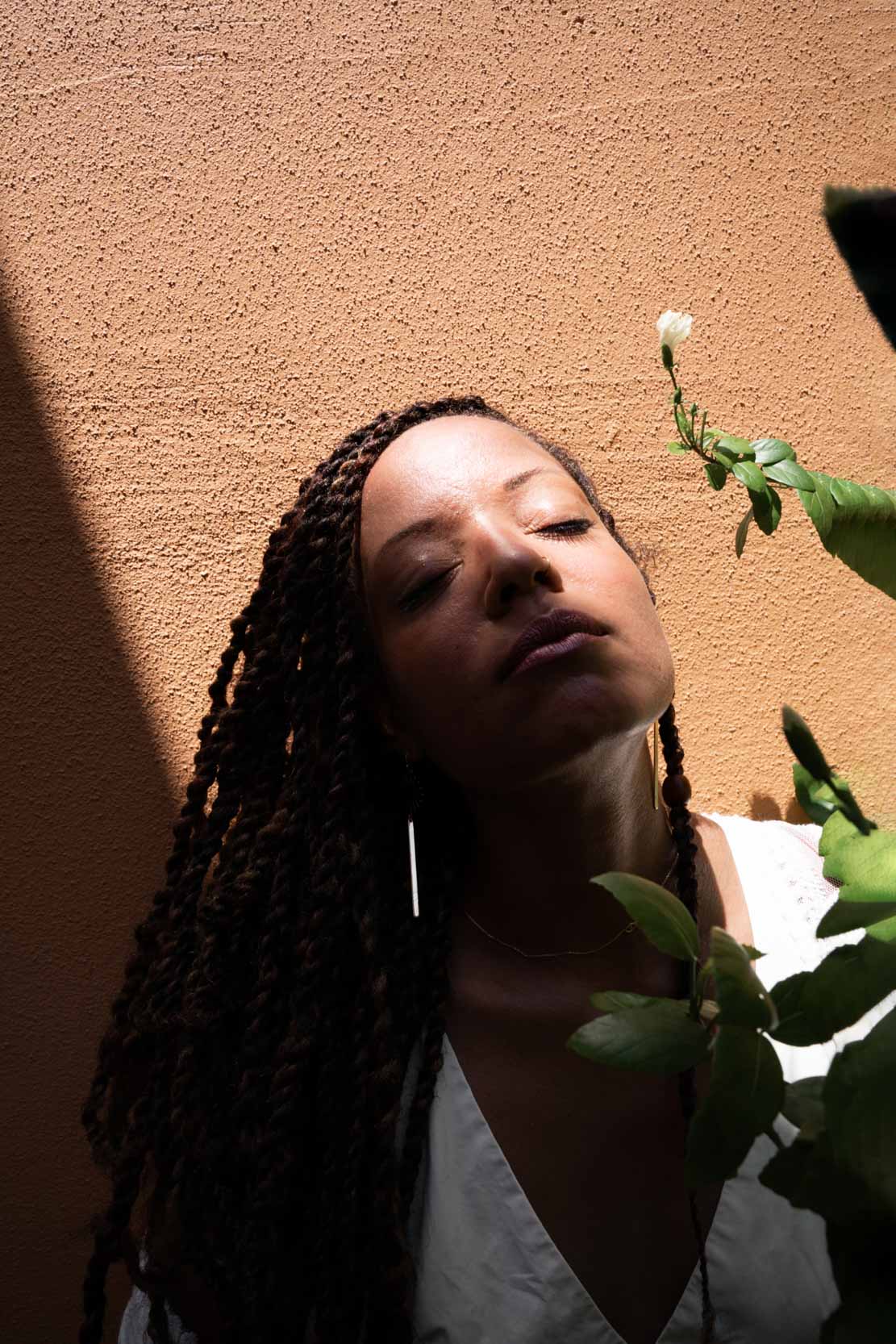 Woman relaxing and meditating in the shade against rustic orange wall in New Orleans City Park Botanical Garden