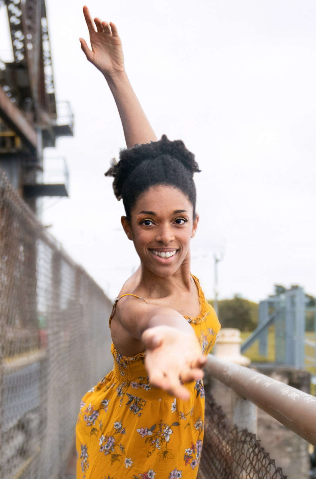 A woman posing and smiling in a beautiful dress on an abandoned bridge in New Orleans