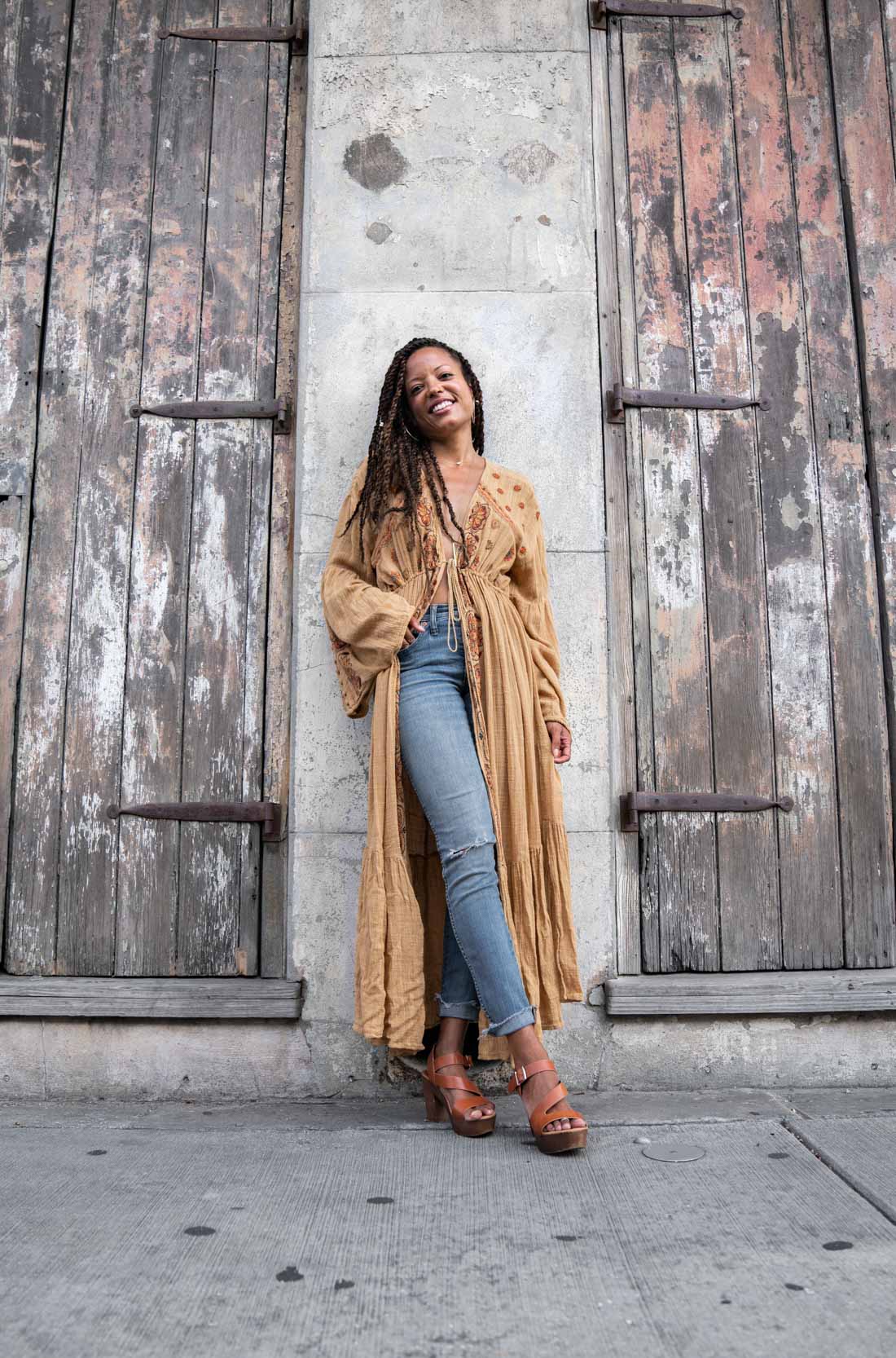 A woman modeling and smiling in a cool outfit on the sidewalk in the New Orleans French Quarter