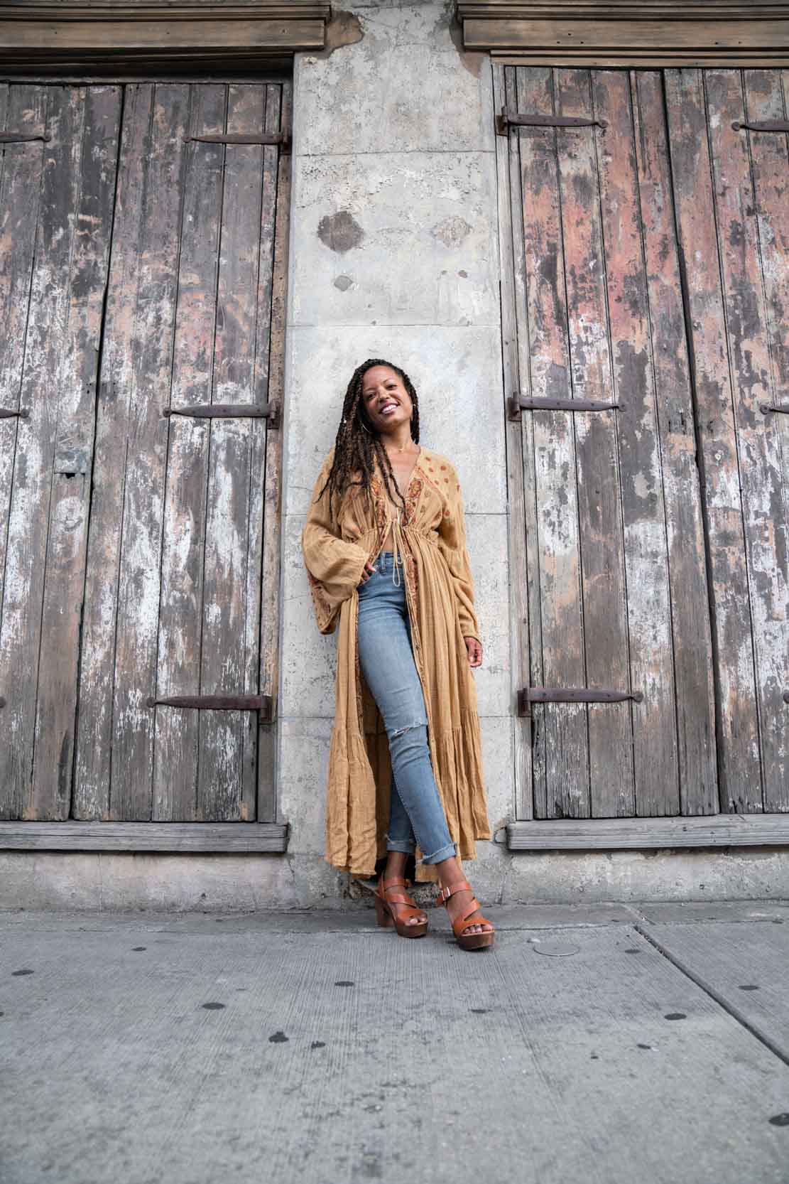 A woman modeling and smiling in a cool outfit on the sidewalk in the New Orleans French Quarter