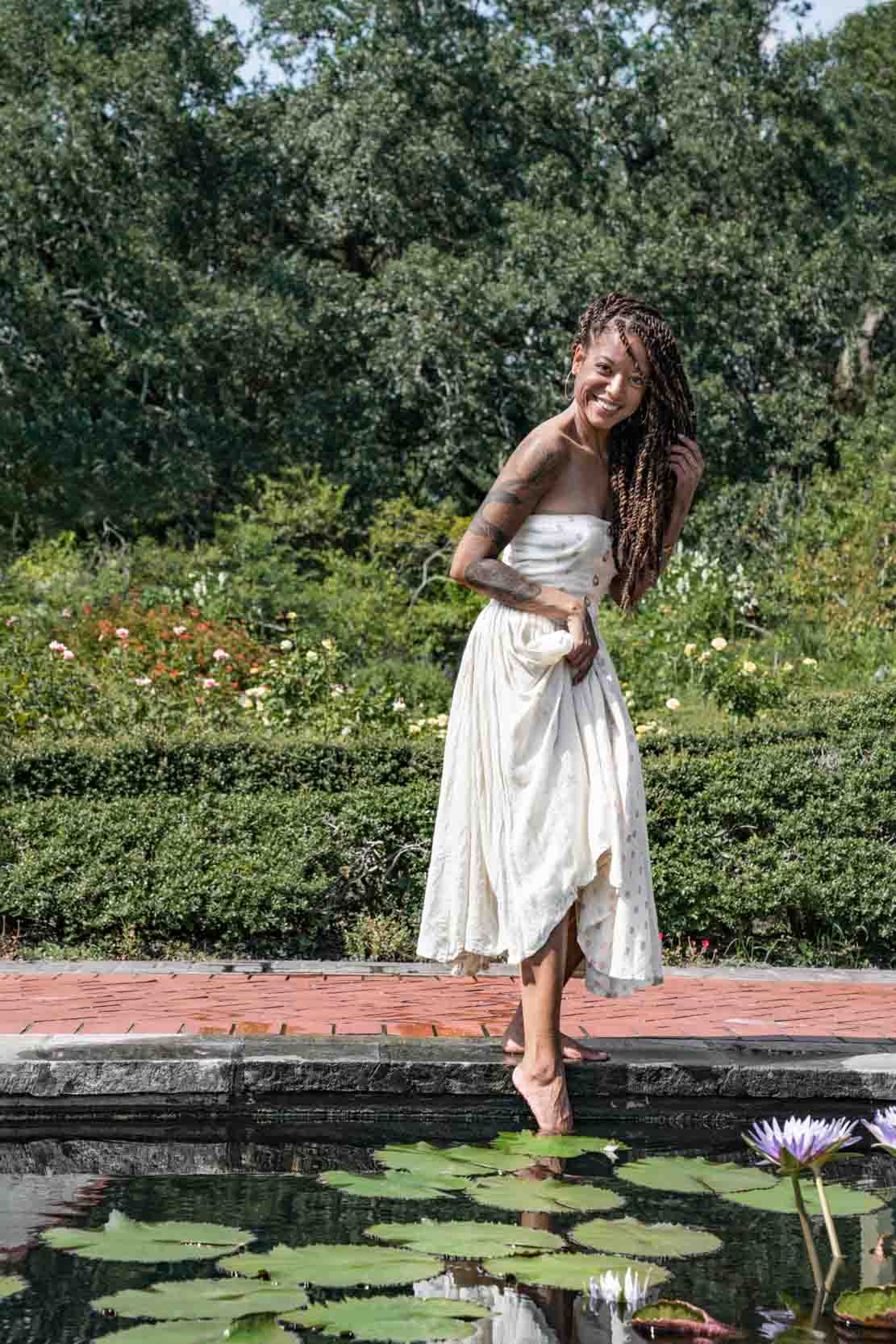 Happy woman dipping her toes into a pond in the New Orleans City Park Botanical Garden w